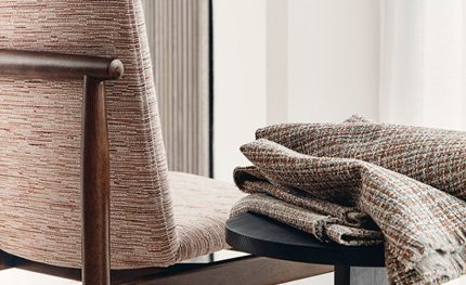 Poltrona e plaid nei tessuti materici semi-uniti della collezione Oxley di Romo. In vendita c’è soltanto il tessuto al metro: arredi e complementi della scena non sono compresi.